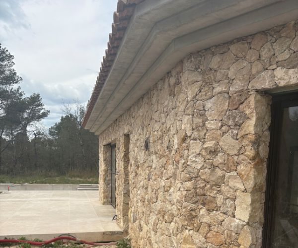 Façade de maison en pierre naturelle avec gouttières maçonnées – NATB