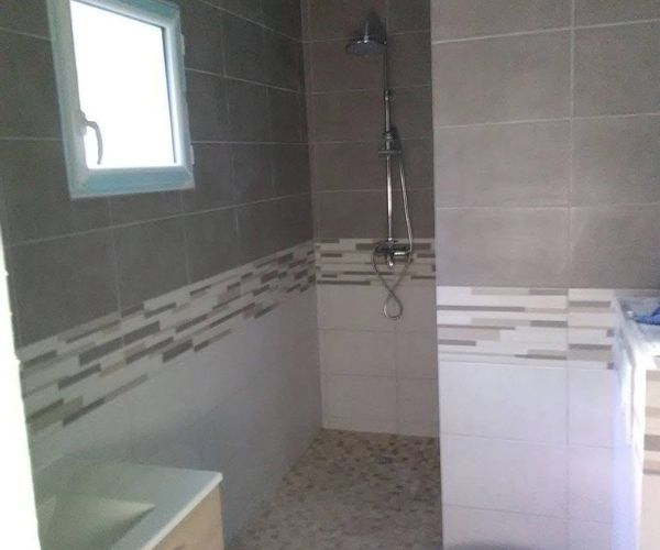 Salle de bain avec douche italienne et carrelage décoratif en pierre – NATB