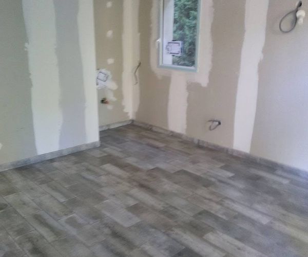 Pose de carrelage imitation bois dans une pièce en rénovation – NATB