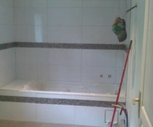 Salle de bain avec baignoire encastrée et carrelage mural blanc et frise grise – NATB