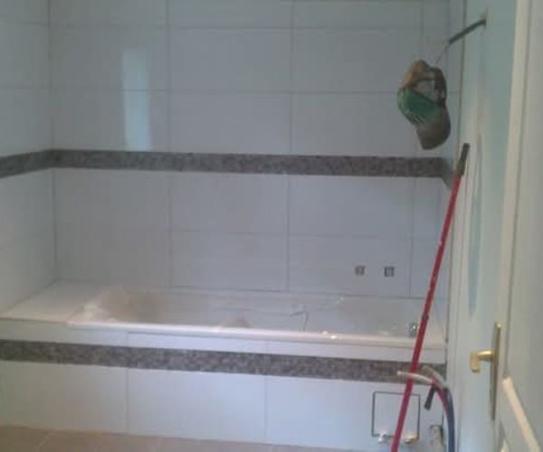 Salle de bain avec baignoire encastrée et carrelage mural blanc et frise grise – NATB