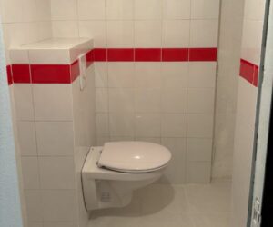 WC suspendu installé dans une pièce carrelée blanc et rouge – NATB