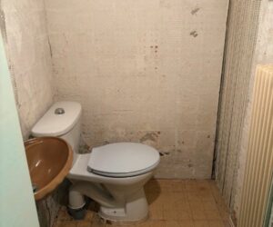 Ancienne salle de bains avec WC et lavabo avant rénovation – NATB