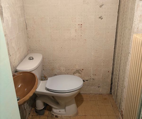 Ancienne salle de bains avec WC et lavabo avant rénovation – NATB