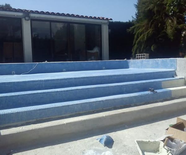 Pose de mosaïque bleue sur les escaliers d’une piscine en rénovation – NATB