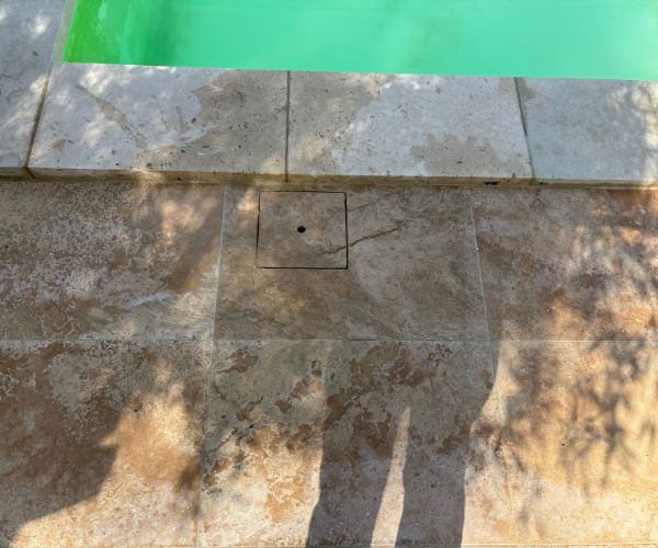 Détail dallage travertin extérieur avec trappe intégrée et finition précise