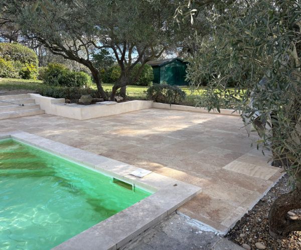 Terrasse en travertin rénovée autour d’une piscine avec finitions soignées